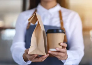 A branded takeaway bag and coffee cup being carried